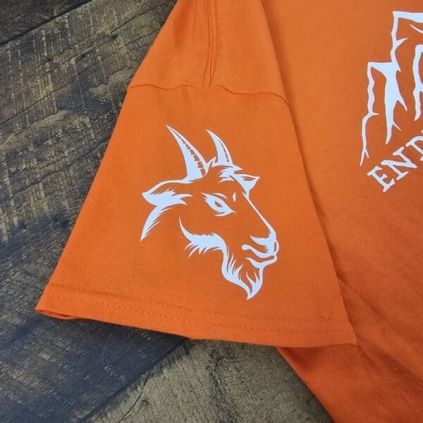 A close up of an orange shirt with a goat on it
