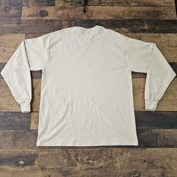 A white long sleeve shirt sitting on top of a wooden floor.