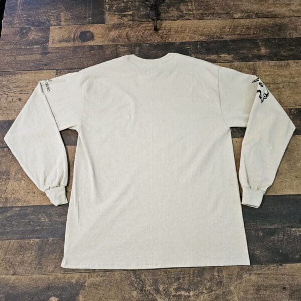 A white long sleeve shirt sitting on top of a wooden floor.