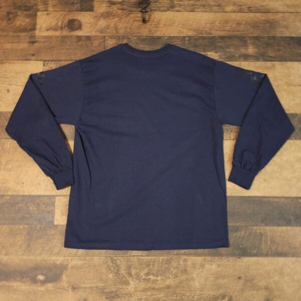 A long sleeve shirt sitting on top of a wooden floor.